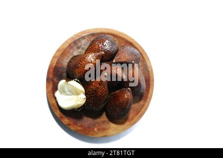 salak fruit or snake fruit in a wooden plate, isolated on a white background Stock Photo