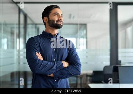 Confident Indian business man leader looking aside standing in office. Stock Photo