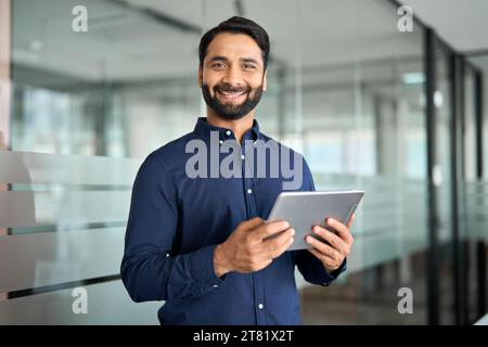Smiling Indian businessman using tab computer working standing in office. Stock Photo