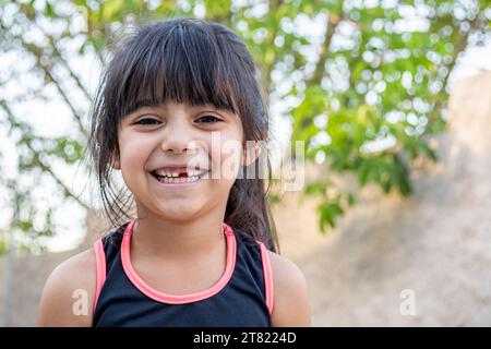 Close-up portrait of her. She is friendly, charming, sweet, curious and cheerful. Little girl outdoors in sports clothing. Stock Photo