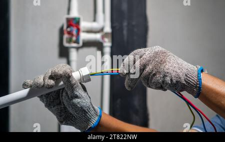 Electrician pulling wire into PVC Conduit. Stock Photo