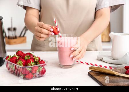Woman with glass of tasty strawberry smoothie at table in kitchen Stock Photo