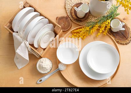 Set of white dishes with cleaning powder and brush on wooden table, top view Stock Photo