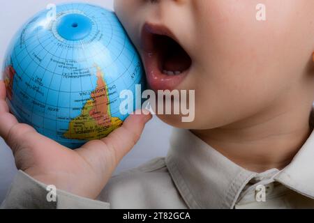 Baby holding a small globe in hand on white background Stock Photo