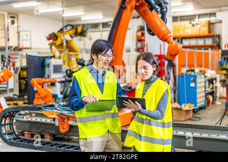 Engineers using digital tablet to control the production of a robotic arm factory Stock Photo