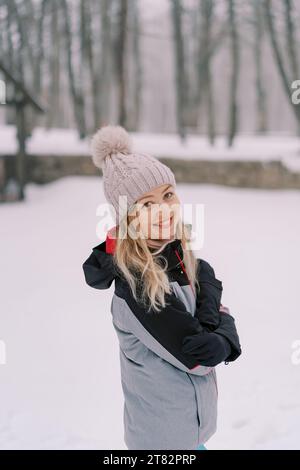 Smiling woman standing in a snowy forest with her arms crossed over her chest Stock Photo