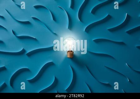 Light bulb glowing on a blue paper background. The concept of spreading a positive vibe Stock Photo