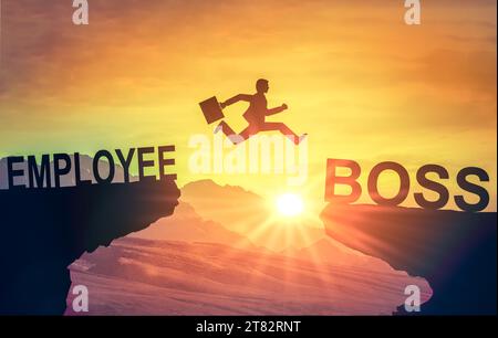 Career jump. Silhouette of man jumping from employee cliff to manager cliff against backdrop of sunset sky. Motivation for career growth. Stock Photo