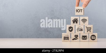IOT. Internet of things , smart home , smart city and network connect concept. Human hand holding wooden cube with IOT icon. devices and connectivity Stock Photo