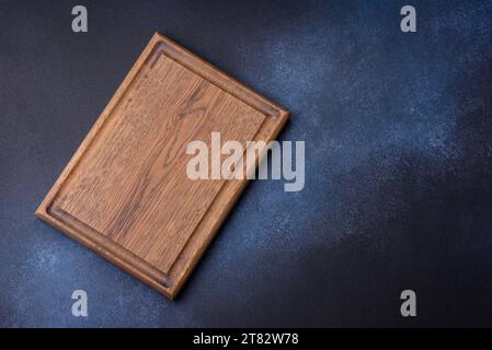 Empty rectangular wooden cutting board on dark concrete background. Cooking at home Stock Photo