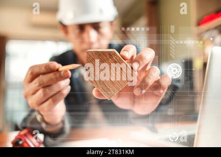 Engineer or Architect uses pencil pointing to wooden home model  for beginning construction development Stock Photo