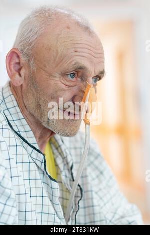 Patient with nasogastric tube on hospital bed waiting for treatment. Positive close up of an elder man waiting for an operation. Enthusiastic approach Stock Photo