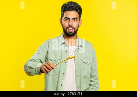 Magician wizard Arabian man gesturing with magic wand fairy stick, making wish come true casting magician spell advertising holidays sale discount. Indian bearded guy isolated on yellow background Stock Photo