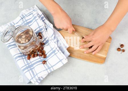 Preparing chestnut liquid soap, cutting buckeye and putting it into a jar with water, alternative homemade detergent for washing clothes Stock Photo