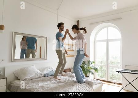 Funny couple jumping on bed in modern bedroom Stock Photo