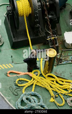 A deckhand secures a ship's mooring line, showcasing the essential skills and strength needed for maritime operations Stock Photo