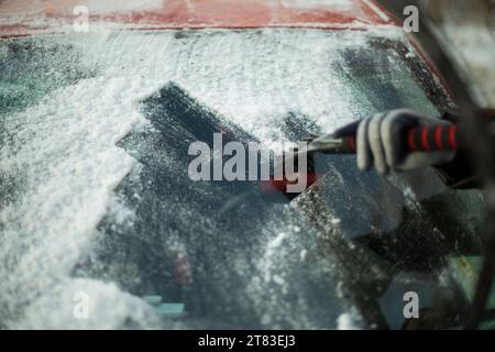 Cleaning glass from snow. Icy windshield. Snow removal. Scraping ice off window. Stock Photo