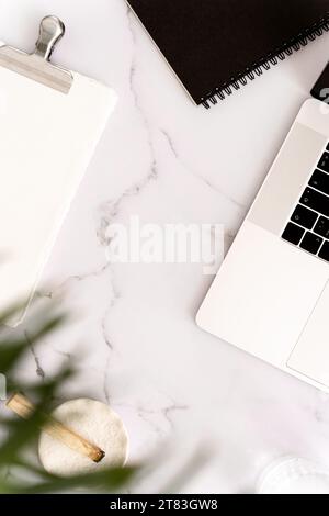 White desk office with laptop, notepads, palo santo stick and green plant flat lay. Top view. Copy space. Modern aesthetic workspace concept. Stock Photo