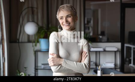 Happy thoughtful business woman in casual standing with folded arms Stock Photo
