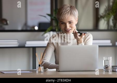 Happy confident business woman recording audio message on smartphone Stock Photo