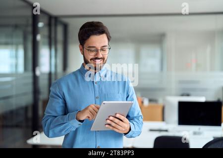 Smiling busy young business man manager using tablet standing in office. Stock Photo