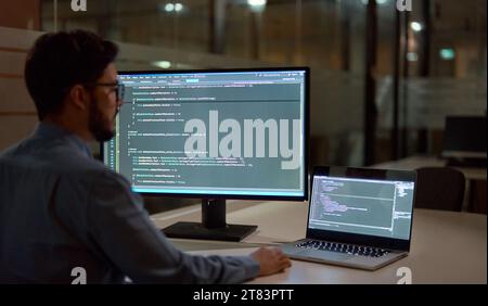 Busy business man software developer working late on computer in dark office. Stock Photo