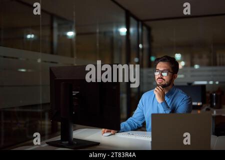 Busy business man software developer using computer working late in office. Stock Photo