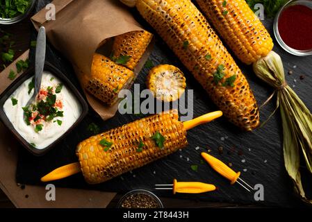 Grilled corn on the cob in caucasian hands on kitchen wooden table background Stock Photo