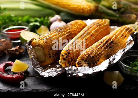 Grilled corn on the cob in tin foil on kitchen table healthy gluten free food background Stock Photo