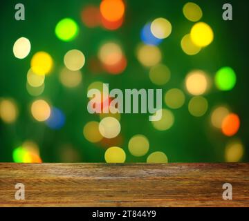 christmas template or background, with multicolored christmas lights and bokeh balls and empty wooden table. Foreground with free space for objects an Stock Photo
