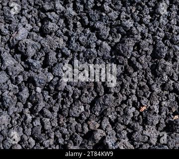 Close-up of black lava rocks on Mount Etna crater, Sicily, Italy. Warm volcanic lava stone formation. Basaltic lava terrain. Surface with volcano Stock Photo