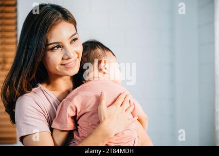 A tender loving biracial mother cradles her small sleeping newborn in her arms Stock Photo