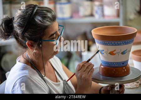 An artisan hand paints traditional Alentejo pottery at Olaria O Patalim, Patalim Pottery Factory, Corval, Alentejo, Portugal creating Portuguese artis Stock Photo