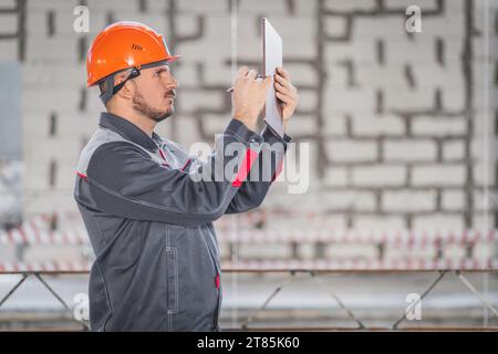 Construction foreman with digital tablet and stylus in hand making sketches for customer, copy space Stock Photo