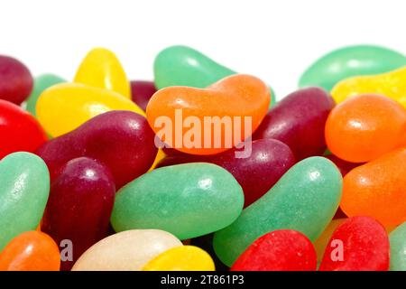 Close up of a pile of colourful jelly beans including red, orange, yellow, green and violet, shot against a white background. Stock Photo