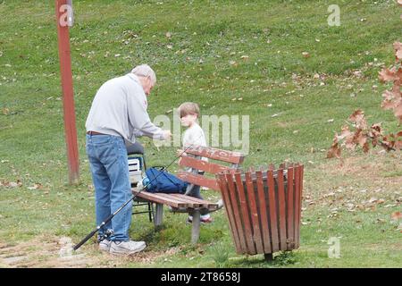 The grandfather is teaching his grandson how to fish. Stock Photo