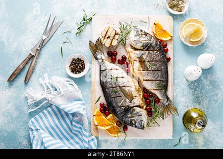 Dorado fish grilled with oranges, cranberries and rosemary, Mediterranean food. Christmas festive healthy dinner, top view Stock Photo