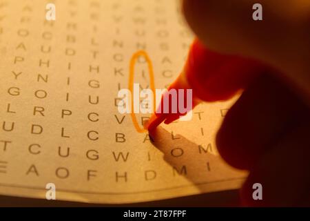 A photo of someone completing a crossword puzzle with an orange marker. Stock Photo