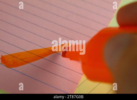 A close up photo of an orange marker highlighting on a pink flashcard. Stock Photo