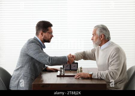 Men shaking their hands during chess tournament at table indoors Stock Photo