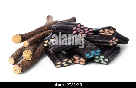 Many tasty candies and dried sticks of liquorice root isolated on white Stock Photo