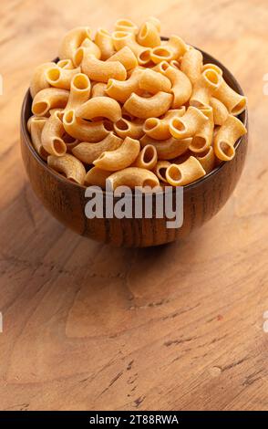 Bowl of Gluten Free Dry Brown Rice Elbow Macaroni Pasta on a Wooden Table Stock Photo