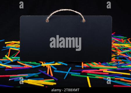 Rectangular shaped black notice board on colorful sticks on black Stock Photo