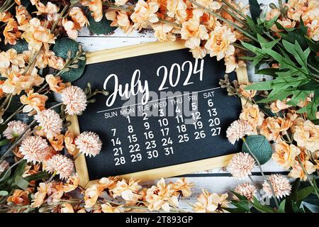 July 2024 monthly calendar with flower bouquet decoration  on wooden background Stock Photo