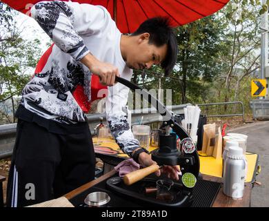 Thai roadside barista pulls an espresso shot using a portable lever press machine in Chiang Mai on17 February 2023. Stock Photo