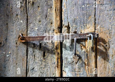 Old metal deadbolt with a lock on a wooden gate Stock Photo