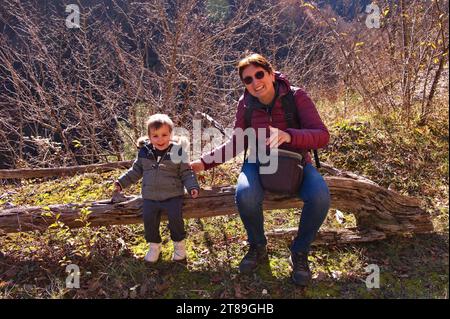 Grandmother and grandchild sitting on the tree trunk in the forest Stock Photo