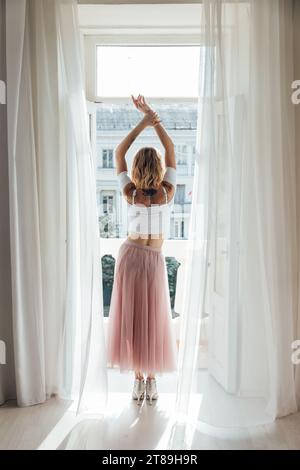 a woman in a pink skirt stands at the door in the room Stock Photo