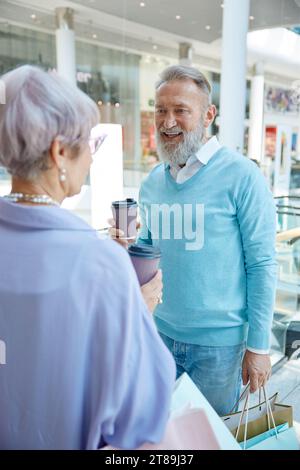 Stylish senior couple drinking coffee taking break during shopping in mall Stock Photo