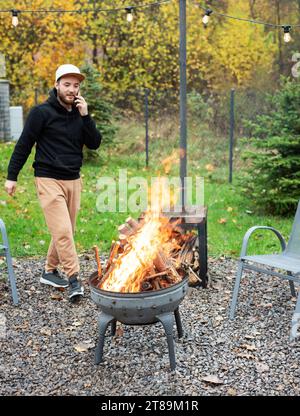 A man lights a barbecue in nature near the house Stock Photo